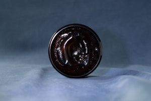 The rich dark texture of Deluxe Pomade in the open jar